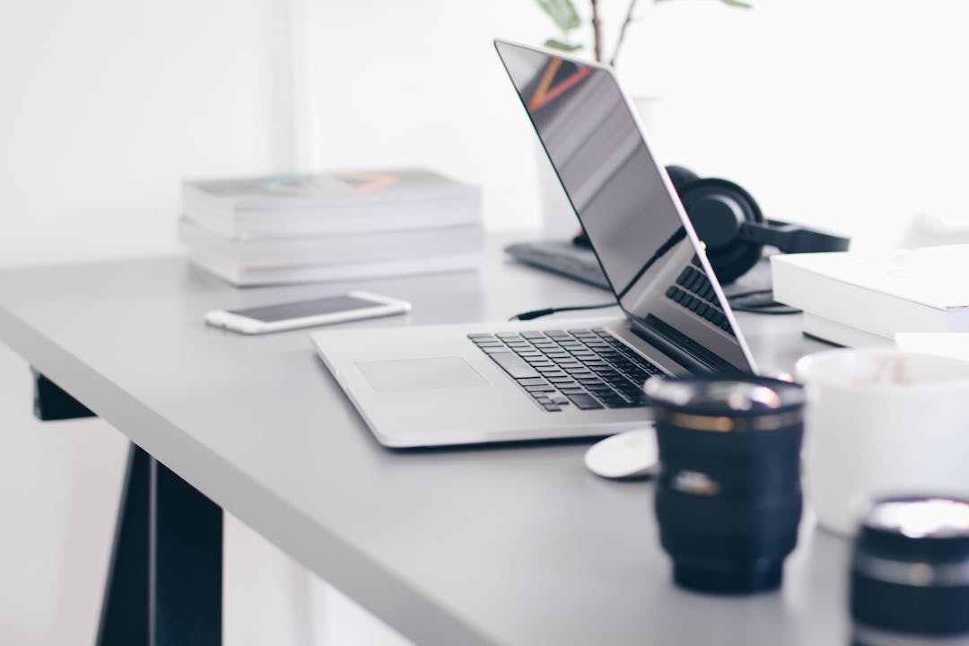 laptop on table with phone and books