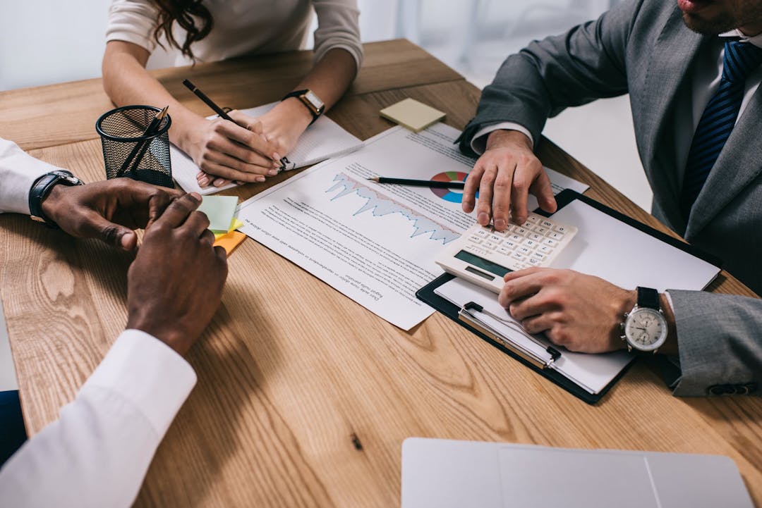 group of people working together while one person is holding a calculator