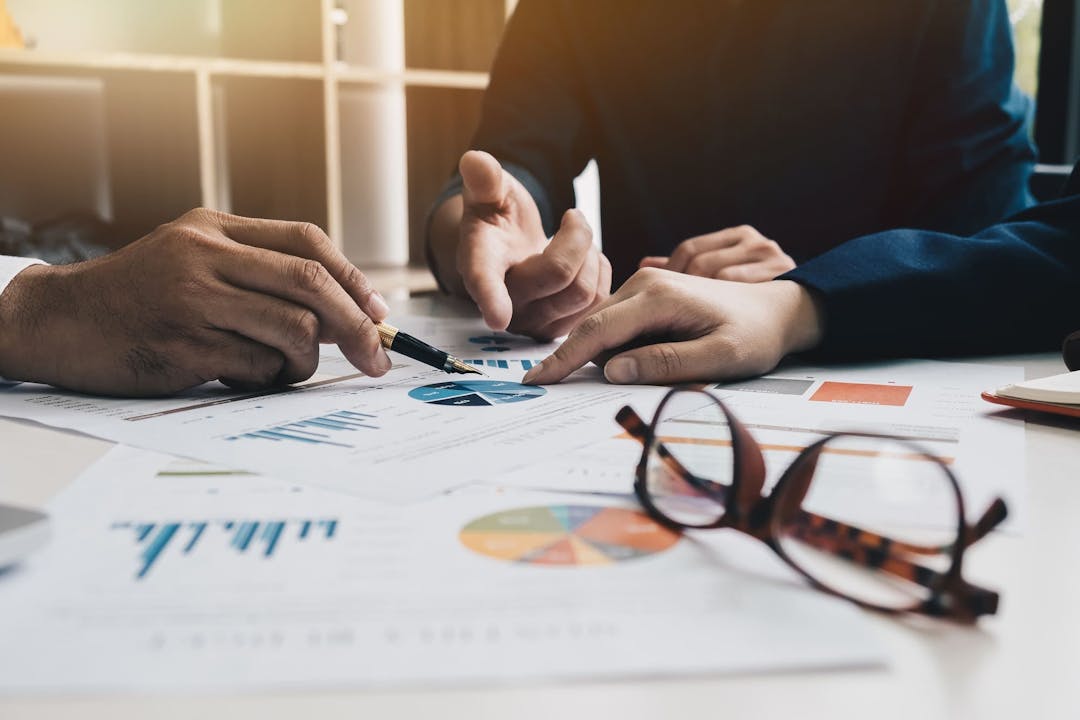 3 individuals looking at a graph; eyeglasses on the table