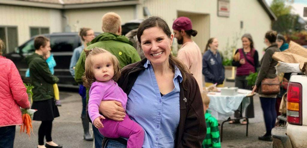 Mom carrying her toddler with people in the background