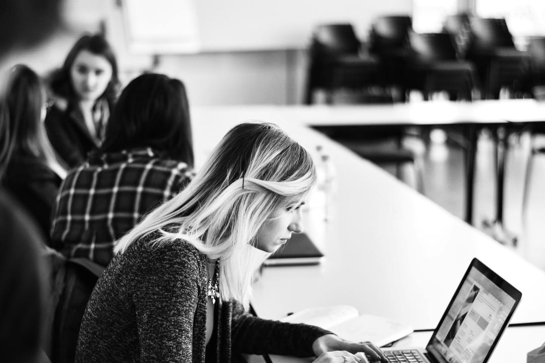 black and white photo of workplace with one group and one female working alone separately